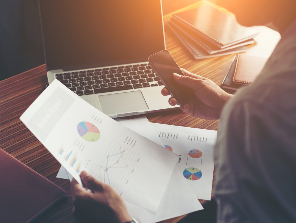 Businessman hands using cell phone with financial report graph a businessman hands using cell phone with financial report graph