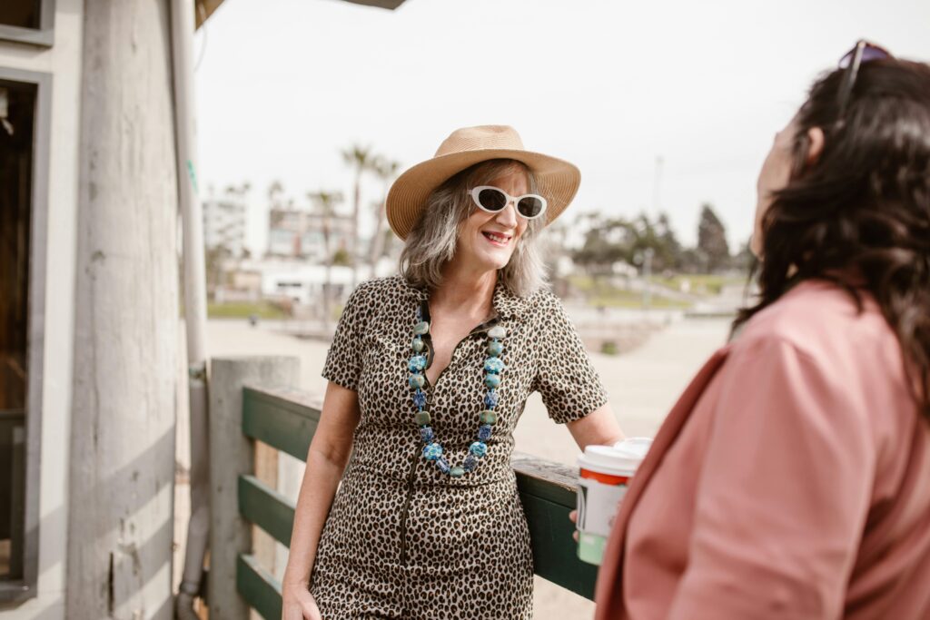 Two stylish women chatting outdoors, showcasing summer fashion and joy.